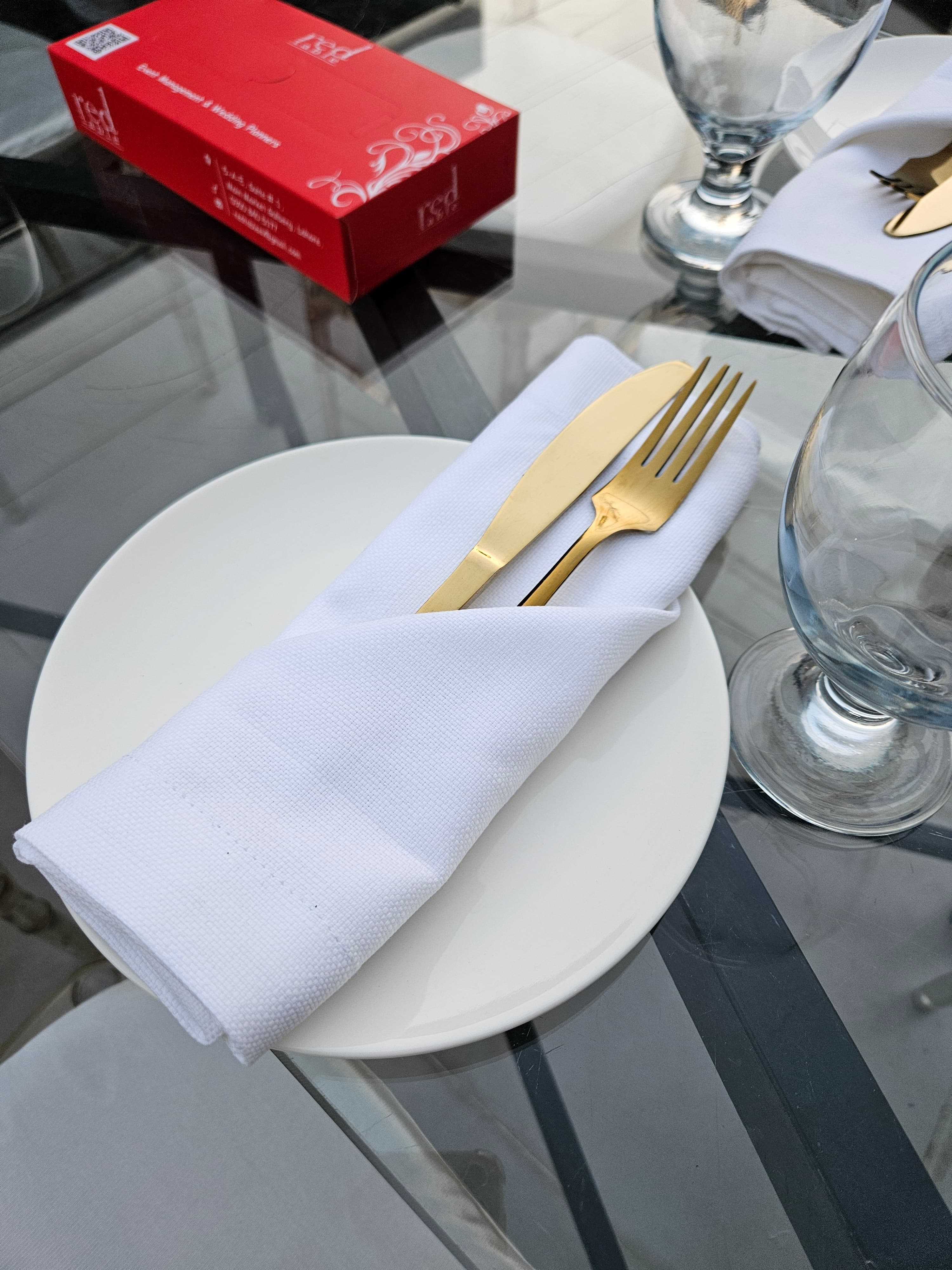 Gold flatware and folded linen at a Red Table place setting